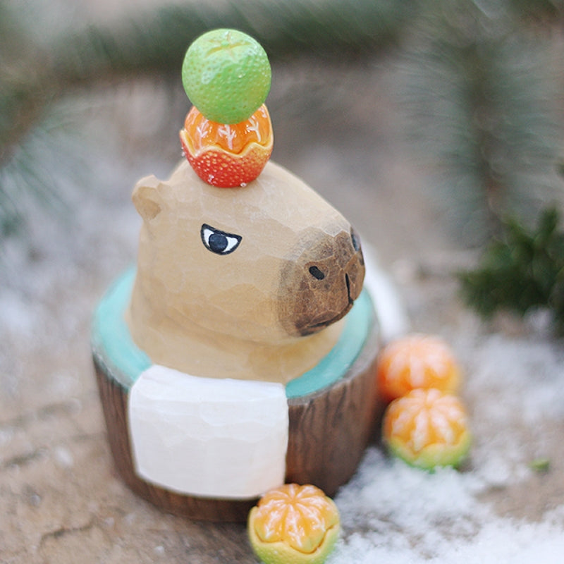 A bubble bath styled capybara sculpture that comes with a small orange accessory for decoration.