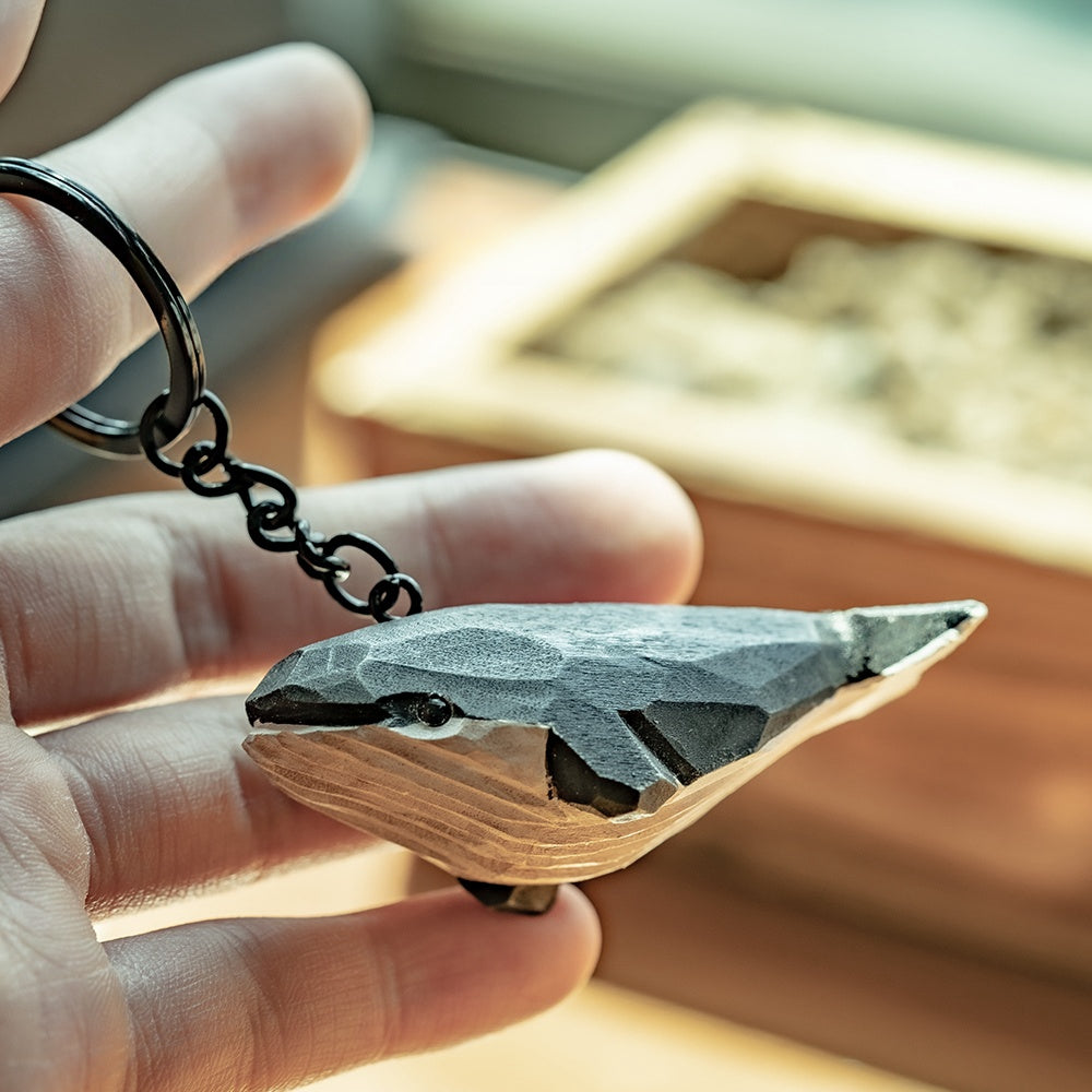 Close-up of a black whale keychain being held in hand, highlighting its texture.