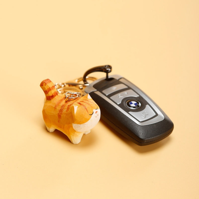 Close-up of Chubby Orange Cat Keychain next to a car key on beige background.