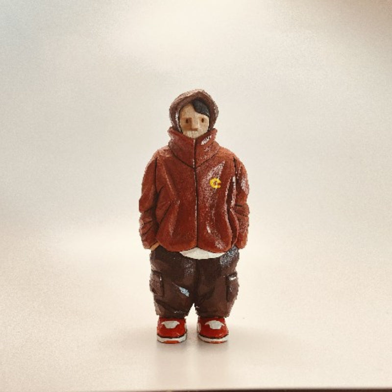 Custom figurine of a young man in a red jacket and brown pants, hand-carved from wood.