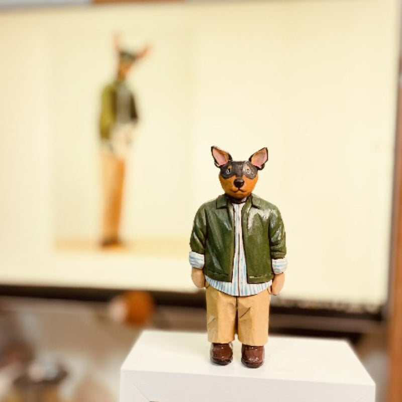 Custom figurine of a person wearing a dog face mask, hand-carved from wood.