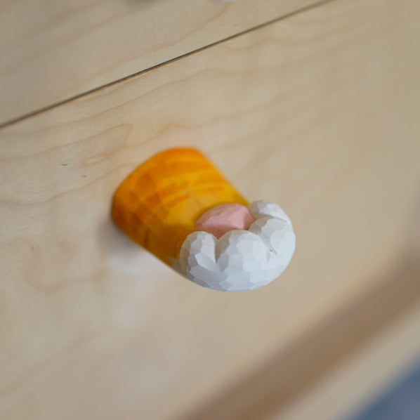 Hand-carved wooden cat’s claw handle mounted on a light-colored wooden drawer, highlighting its smooth finish.