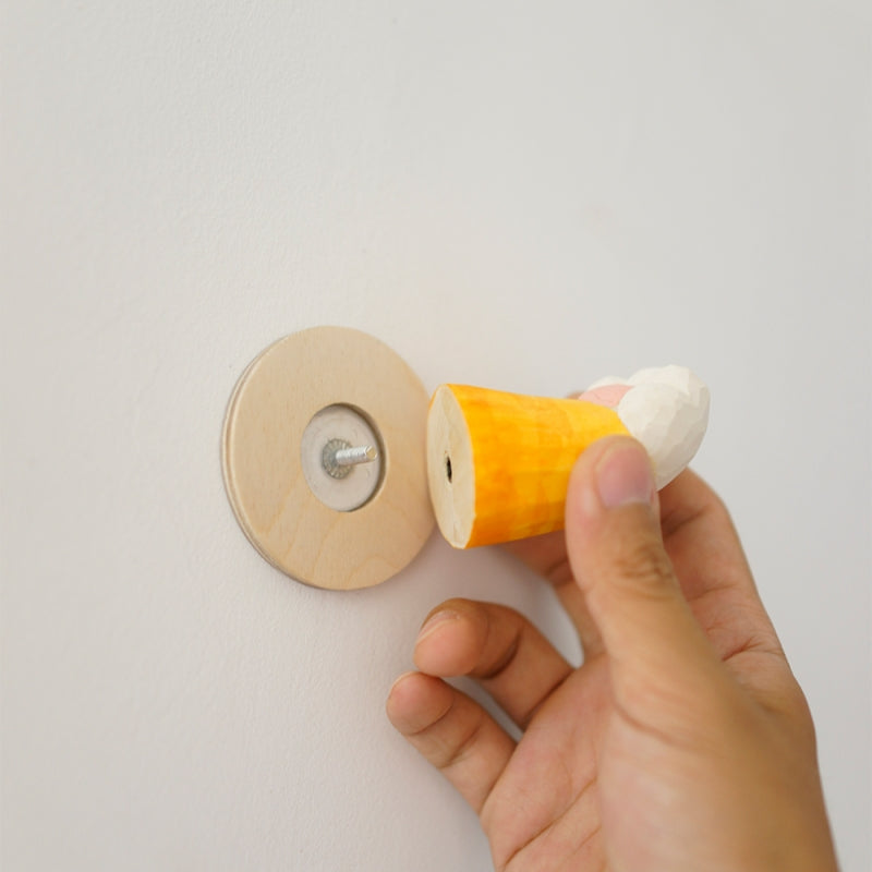 Hand attaching a handcrafted wooden cat’s claw handle to a wall mount, demonstrating its easy installation.