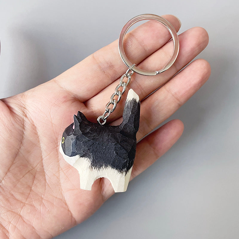 Close-up of a person holding a Holstein cat keychain, showcasing its detailed black and white painted design.