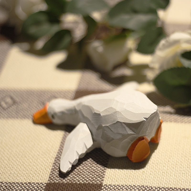 Wooden duck figures are set on a tablecloth-covered dining table.