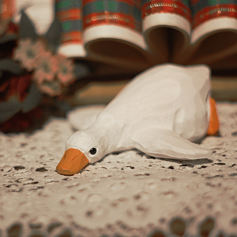 Lying wooden duck figures on a floor stand.