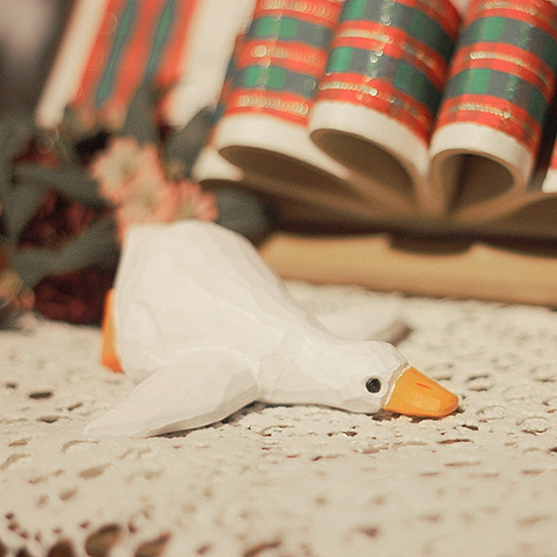 Close-up of a lying wooden duck figure in a holiday scene.