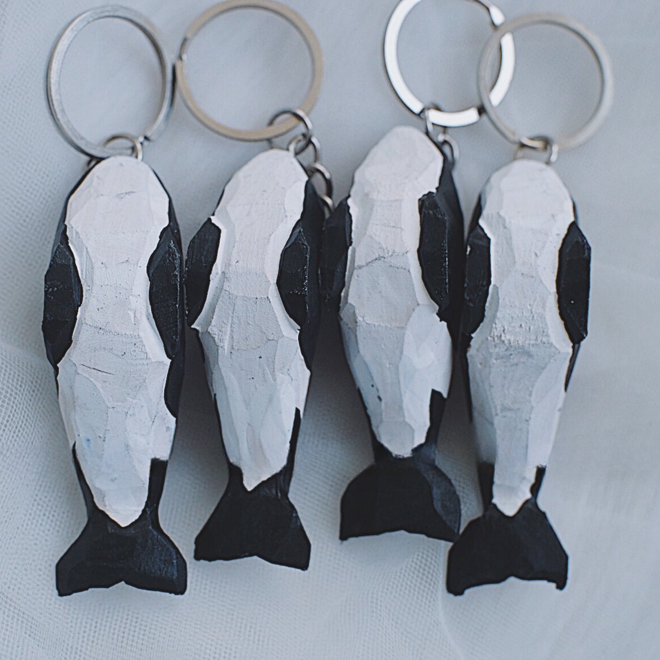 Back view of four hand-carved orca whale keychains showing the intricate details of the carvings.