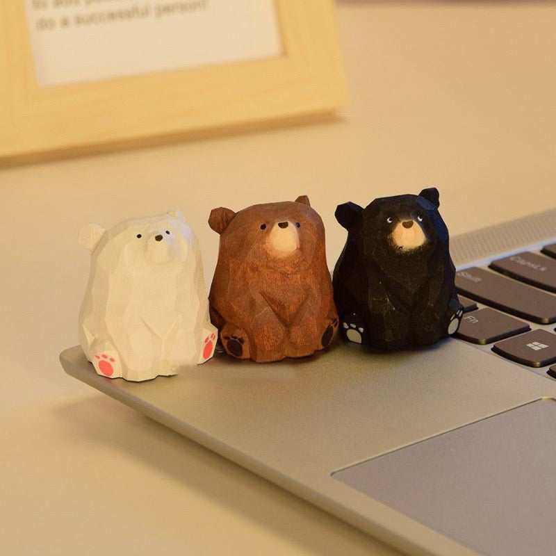 Three wooden bear statues placed on laptop suitable for desk decorations.