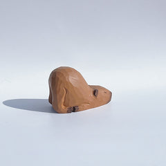 Rear side view of sleeping capybara figurine, hand-painted wooden statue.