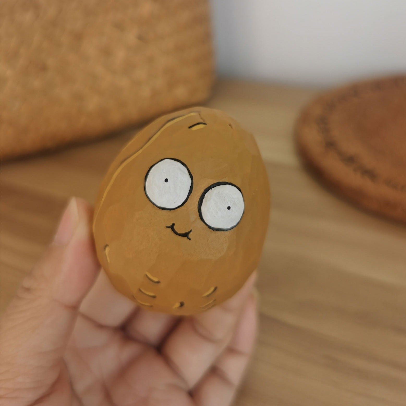 Close-up of a hand holding a Wall-nut figurine with a cute, smiling face.