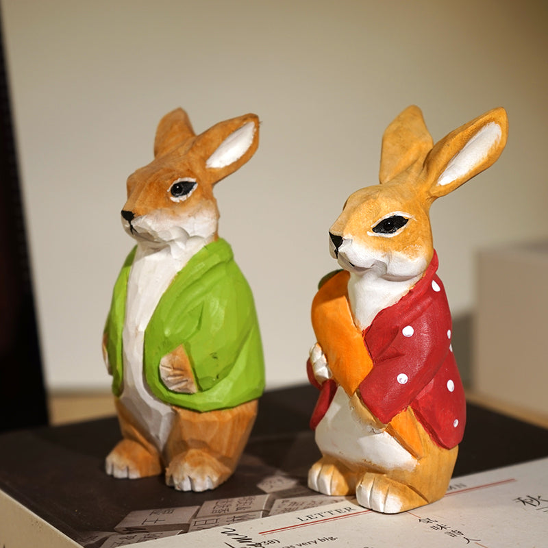 Hand-carved bunny couple wooden figurines in colorful attire standing together.