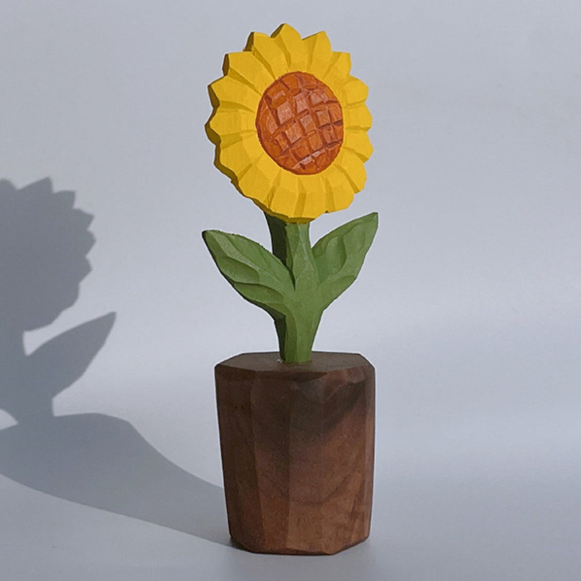 Hand-carved wooden sunflower sculpture on a wooden base, showcasing detailed craftsmanship.